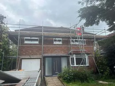 Scaffolding along the front of a detached house with a garage