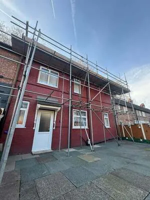 Scaffolding on a red-painted semi-detached house