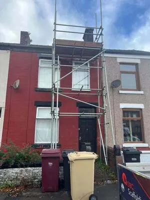Scaffolding on the front of a red-painted terraced house