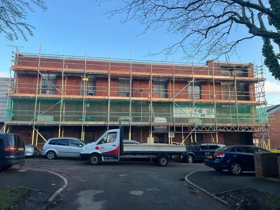 Access scaffolding along a three-storey brick building with the SBC Scaffolding van