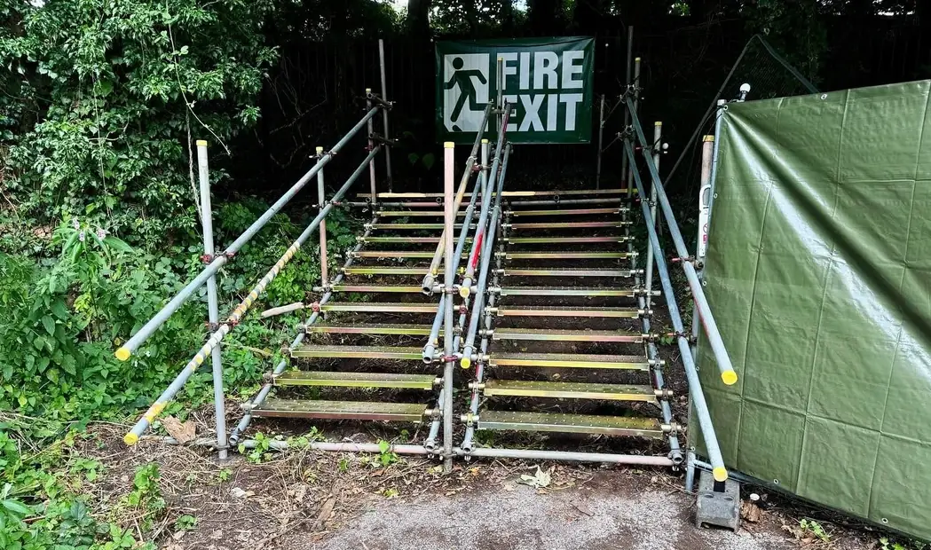 Scaffold staircases with handrails leading to a fire exit