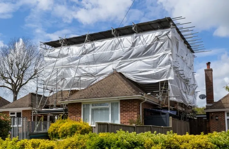 Temporary roof sheeting on scaffolding over a house